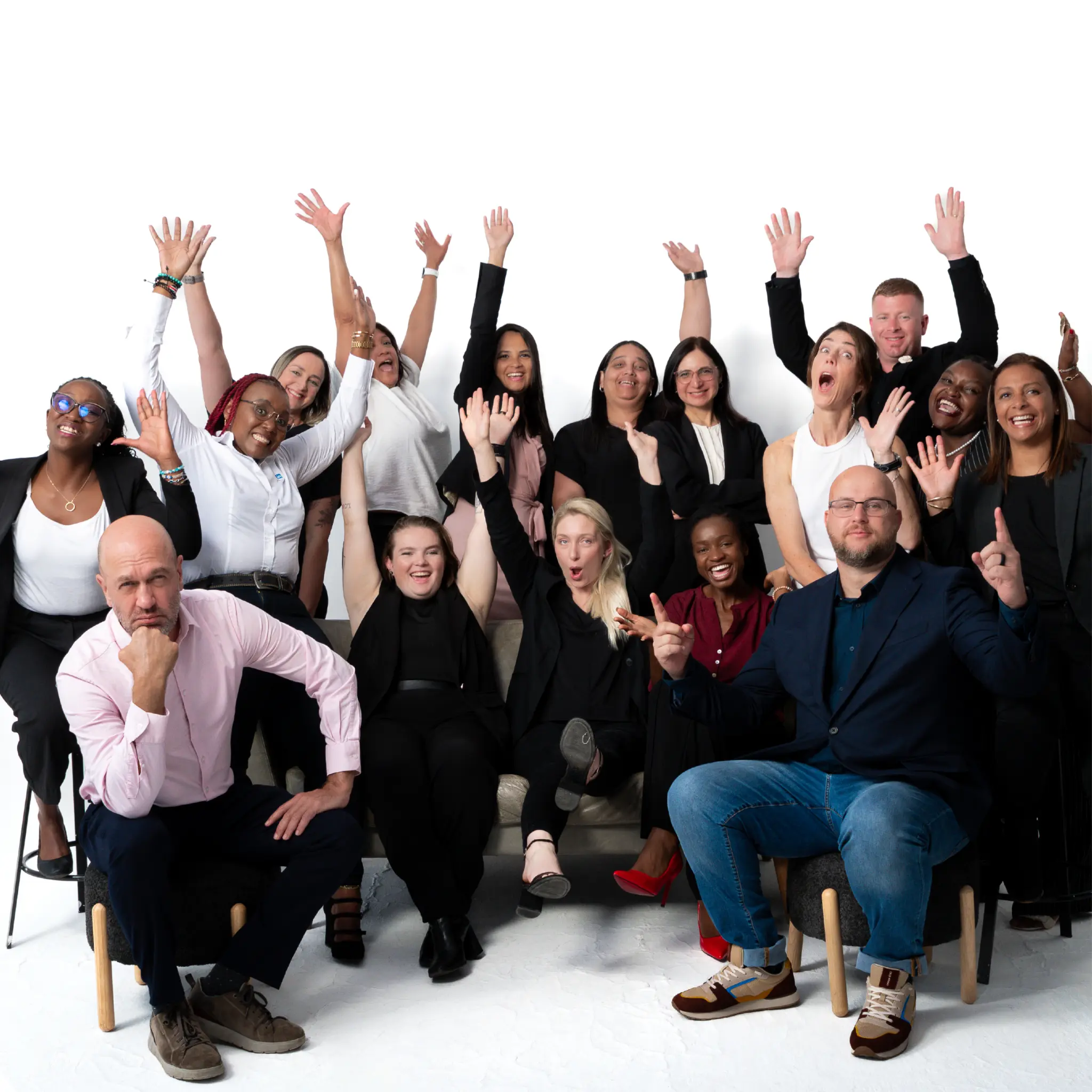 Group of diverse people (the Turnleft team) smiling and raising hands in excitement against white background.
