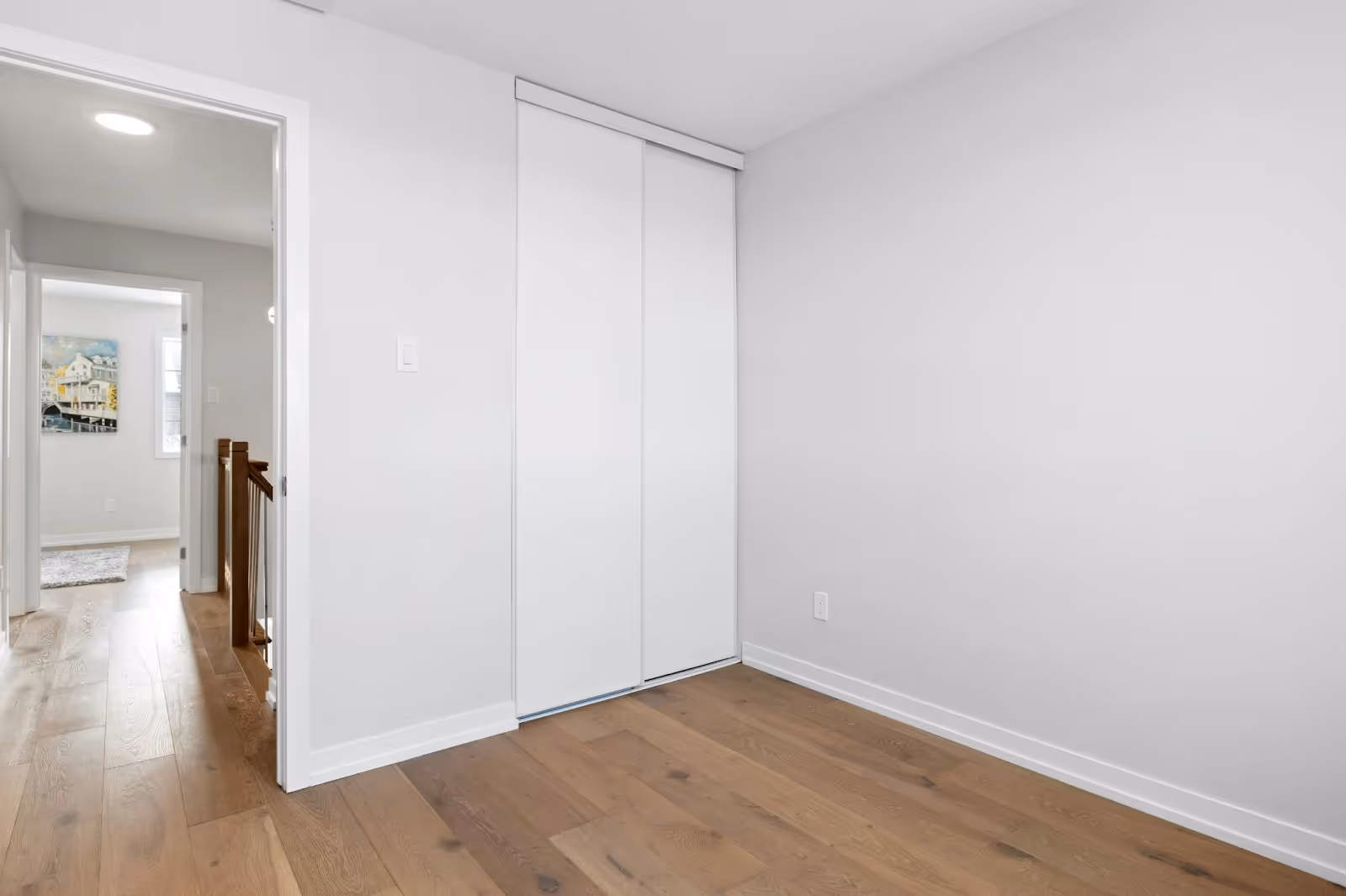 Empty white room with engineered hardwood flooring