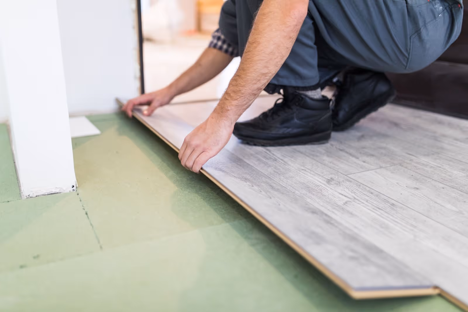 Man laying  luxury vinyl flooring showing wear layer and core