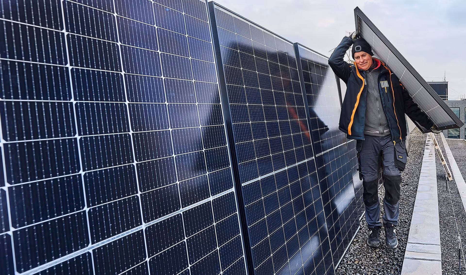 Ein Arbeiter trägt ein Solarpannel zur Montage