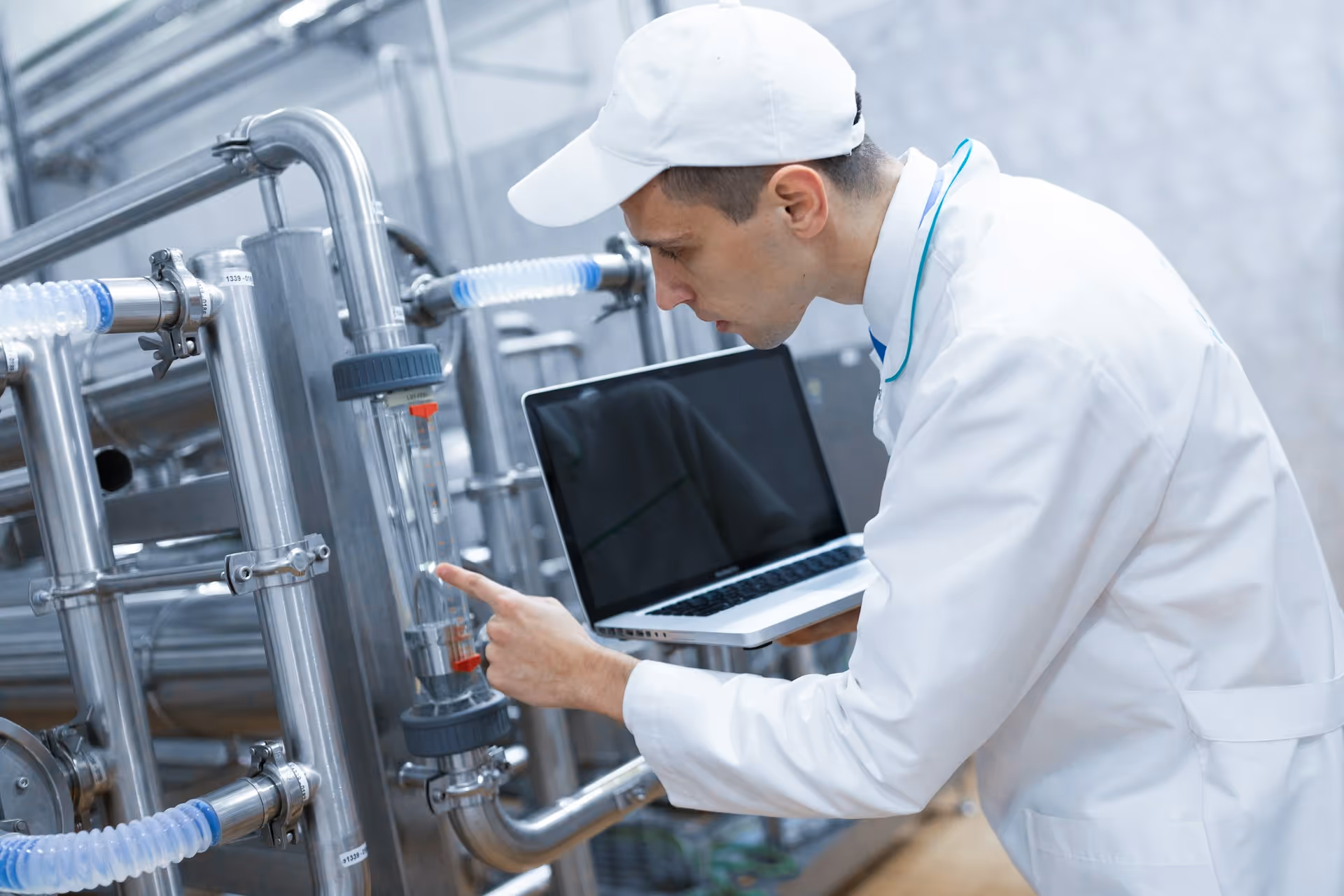 Technicien en tenue blanche utilisant un ordinateur dans une installation industrielle.