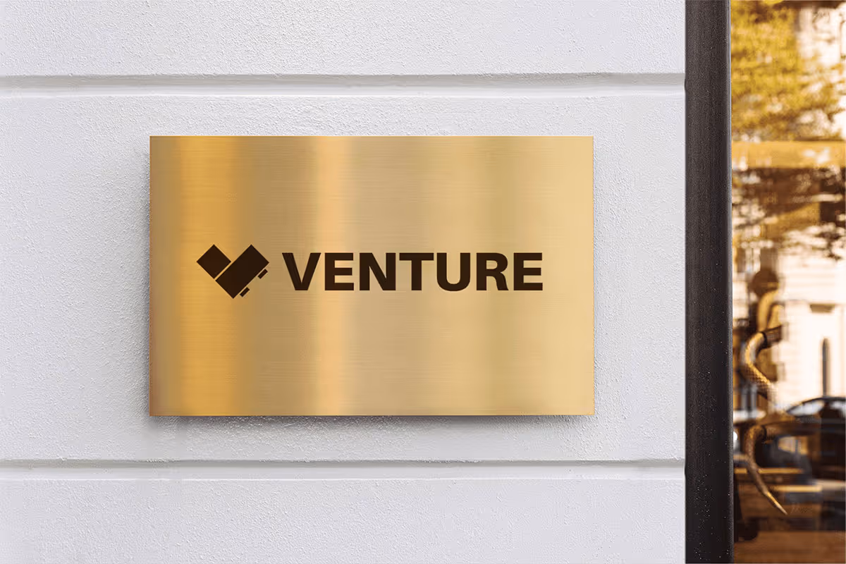 Gold plaque featuring the Venture logo in an interior.