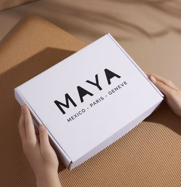 White box featuring the Maya logo, held in both hands.