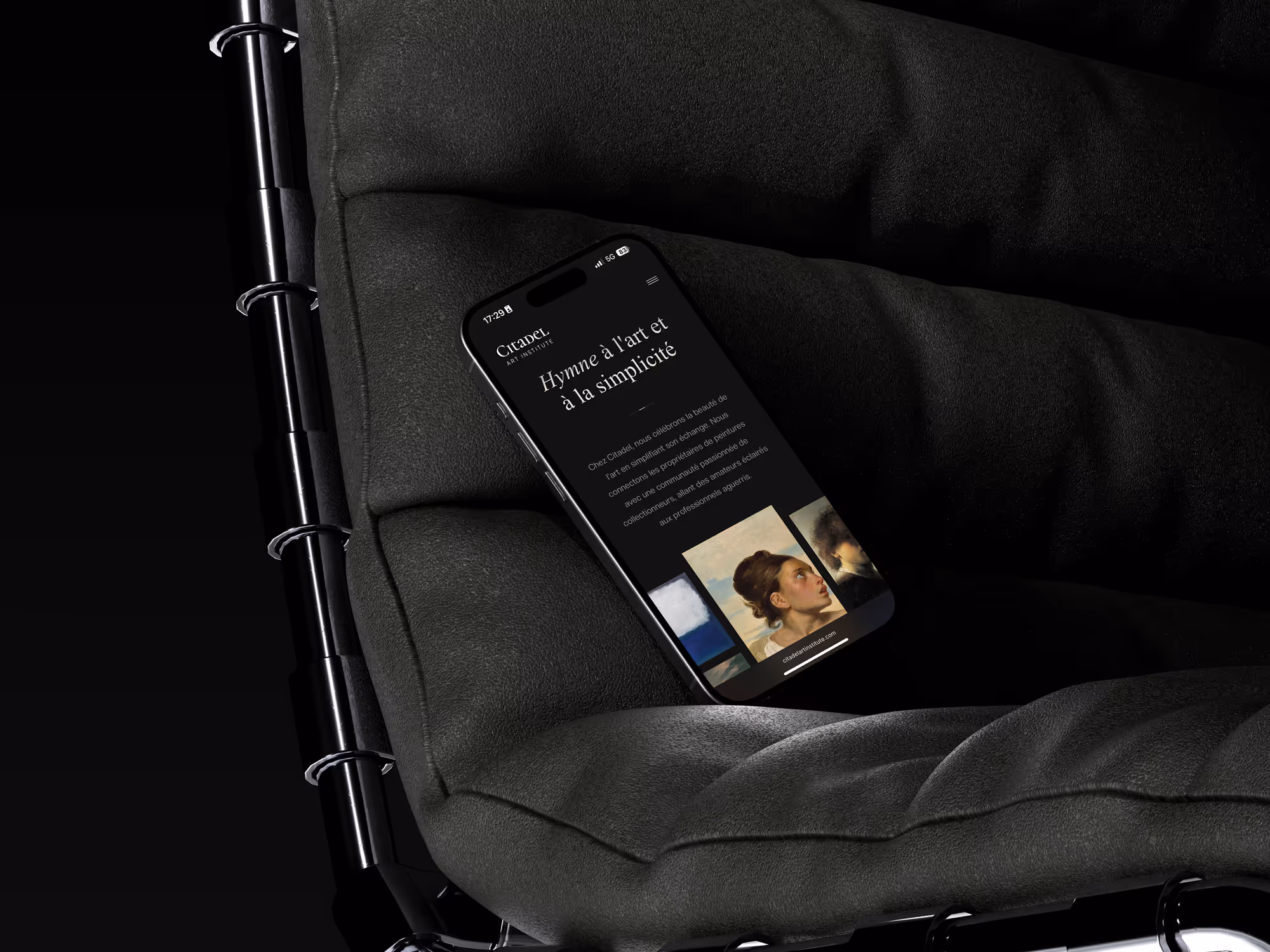 Smartphone on a dark cushioned chair displaying Citadel Art Institute French webpage on art and simplicity.