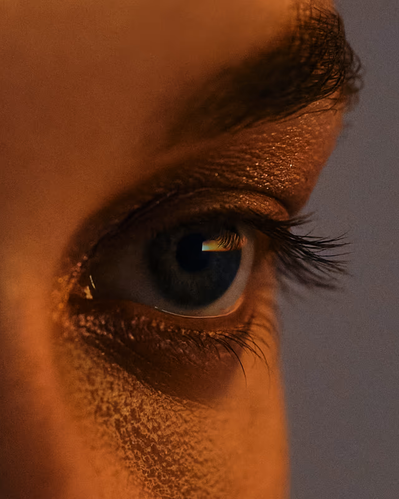 Gros plan d'un œil humain avec une lumière se reflétant sur l'iris et les cils.