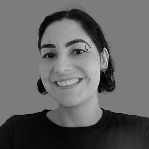 Mulher de cabelo médio com piercing na sobrancelha sorrindo.