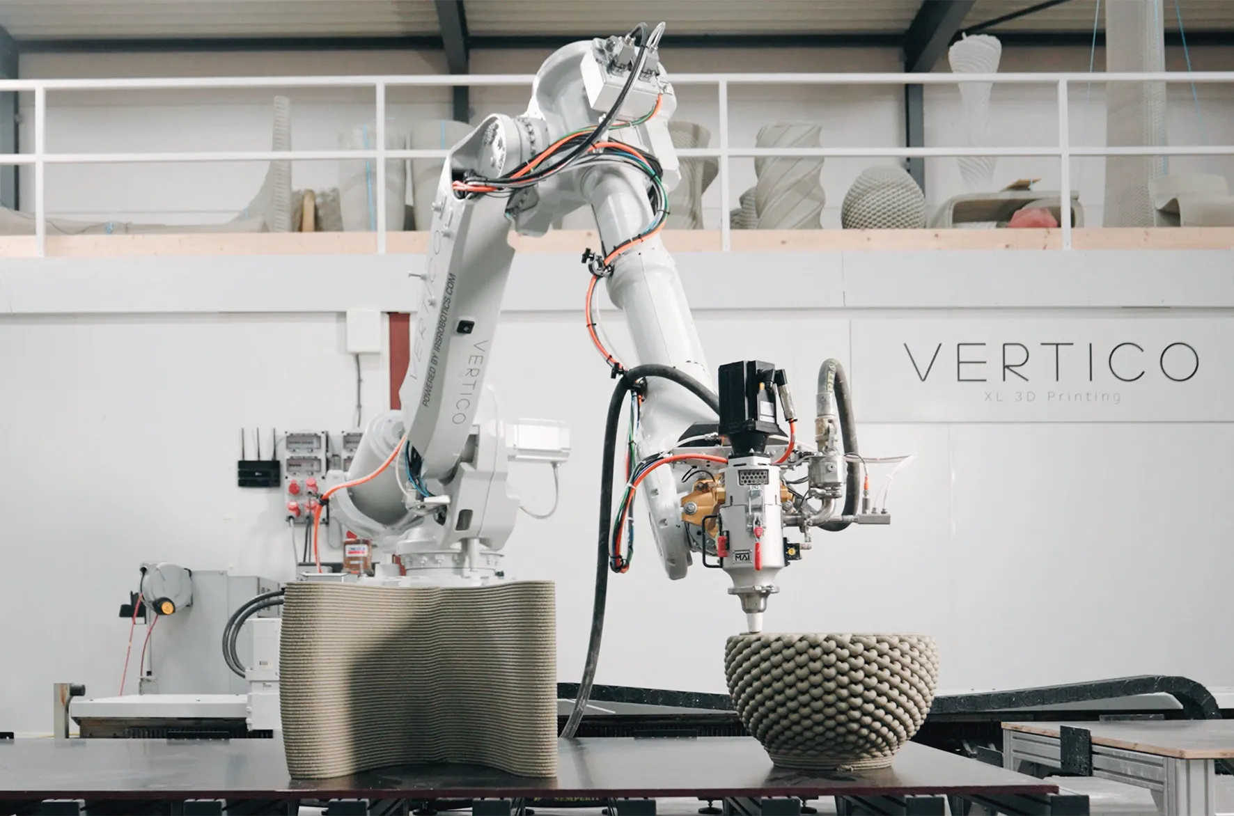 3D concrete printer creating textured cylindrical objects in industrial workspace