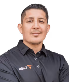 Man with short dark hair wearing a black polo shirt with the Ttello logo, looking at the camera with folded arms.