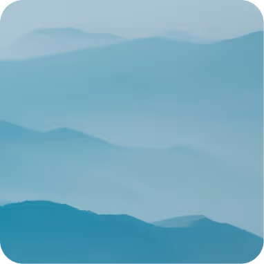 Layered blue mountains fading into mist under a pale sky.