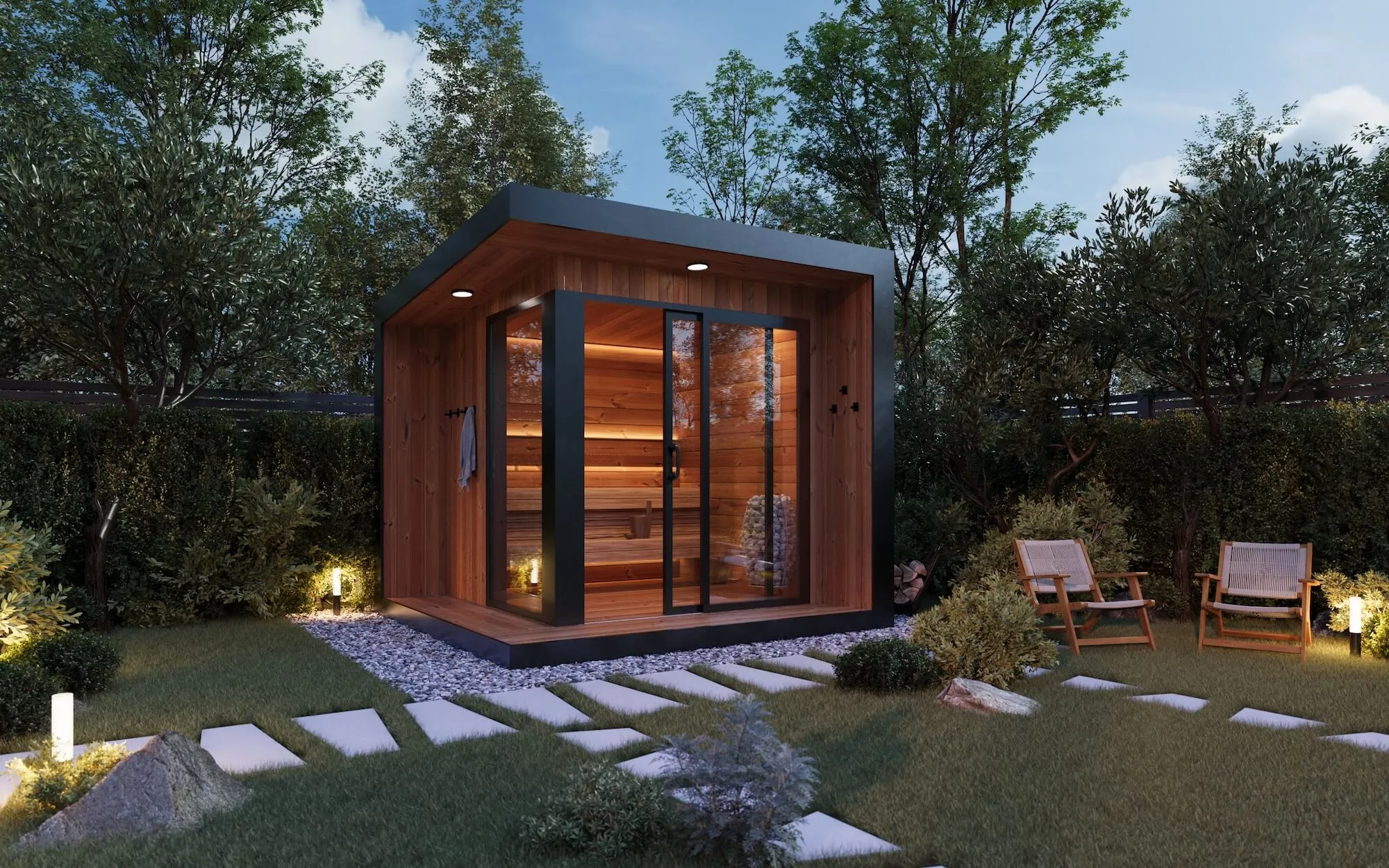 Modern wooden garden sauna with glass sliding doors illuminated inside, surrounded by lush greenery and outdoor chairs on a grassy lawn.