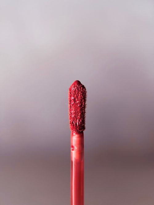 a lip product applicator against a soft grey background
