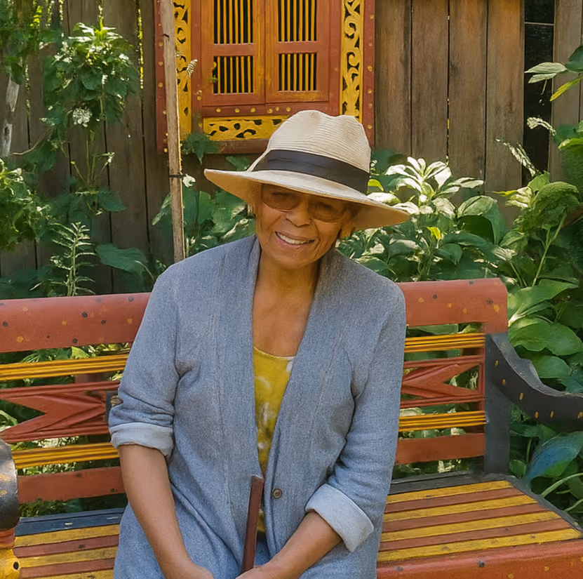 A smiling woman sitting on a bench with hat and glasses plumbing customer