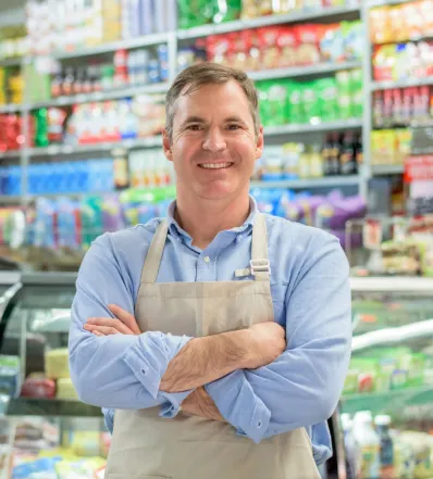 Store owner in an apron standing in a grocery aisle