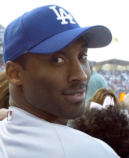 Person wearing blue LA Dodgers baseball cap and white jersey at a stadium, looking sideways