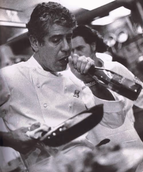 A black and white photo of chef Anthony Bourdain working in the kitchen
