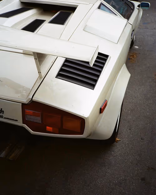 Rear view of white Lamborghini Countach sports car showing spoiler, engine vents, and red taillights