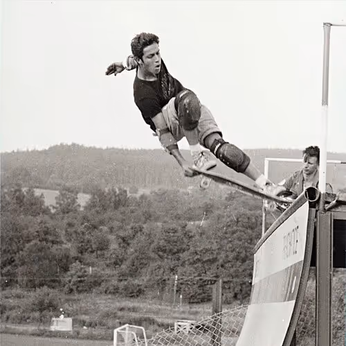 Black and white photo of skateboarder performing aerial trick off a ramp