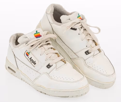 Vintage white Apple sneakers with rainbow logo on tongue and side, showing wear
