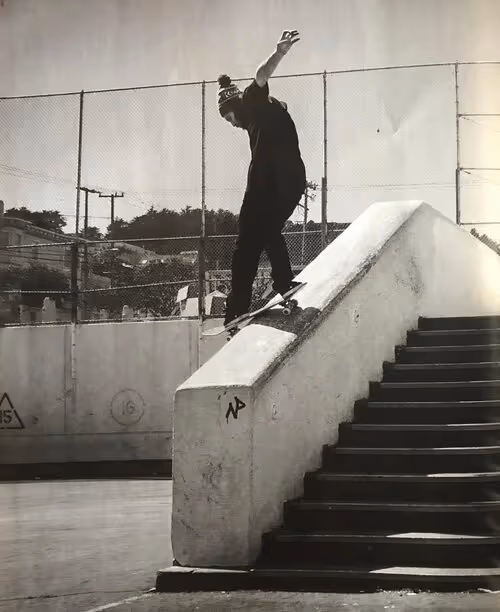 Skateboarder grinding on concrete handrail of staircase in black and white urban skatepark photo