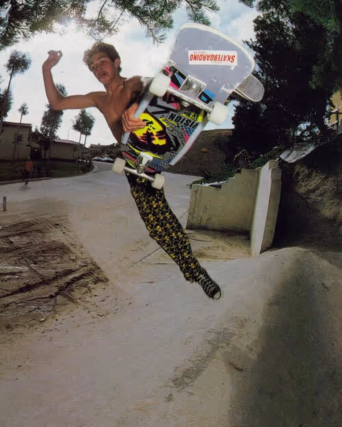 Young skateboarder performing aerial trick with vintage Vision skateboard in backyard pool or ramp