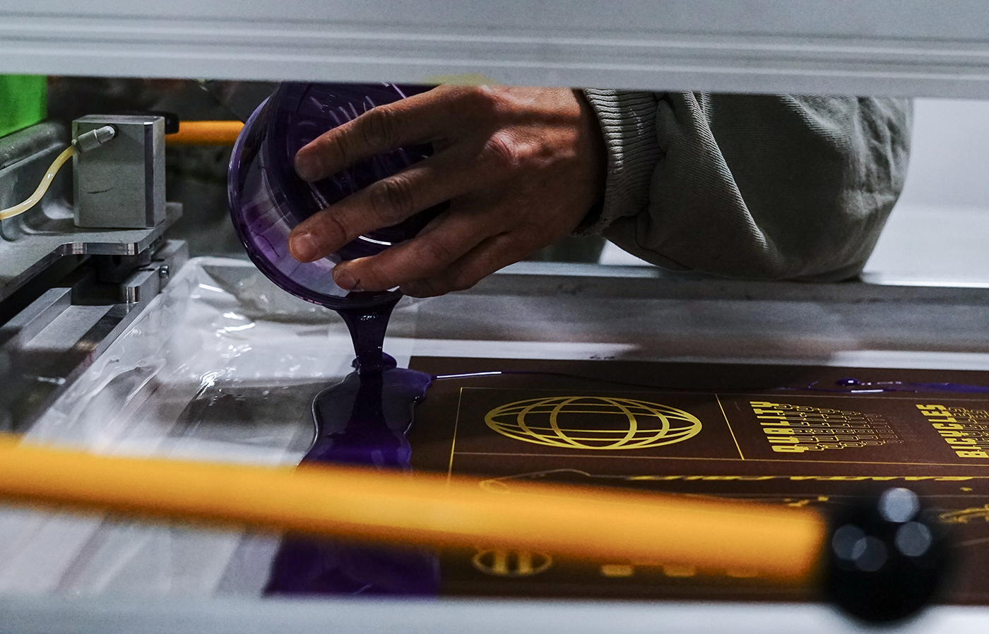 A photo of a press operator putting water based ink into a screen.