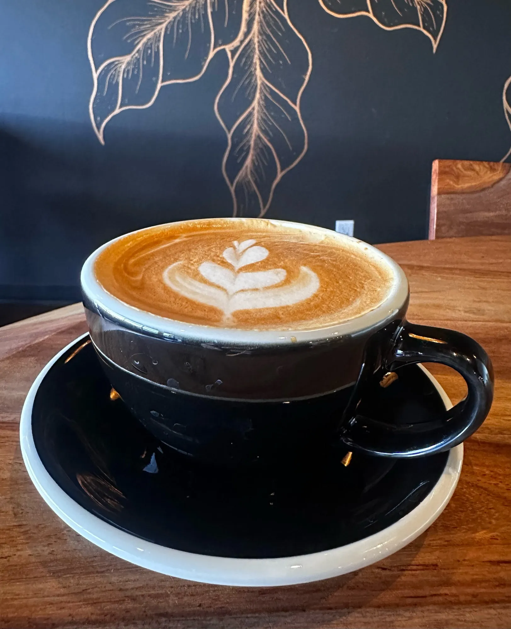 Latte art served in a black cup at Copper Cup Coffee Co.