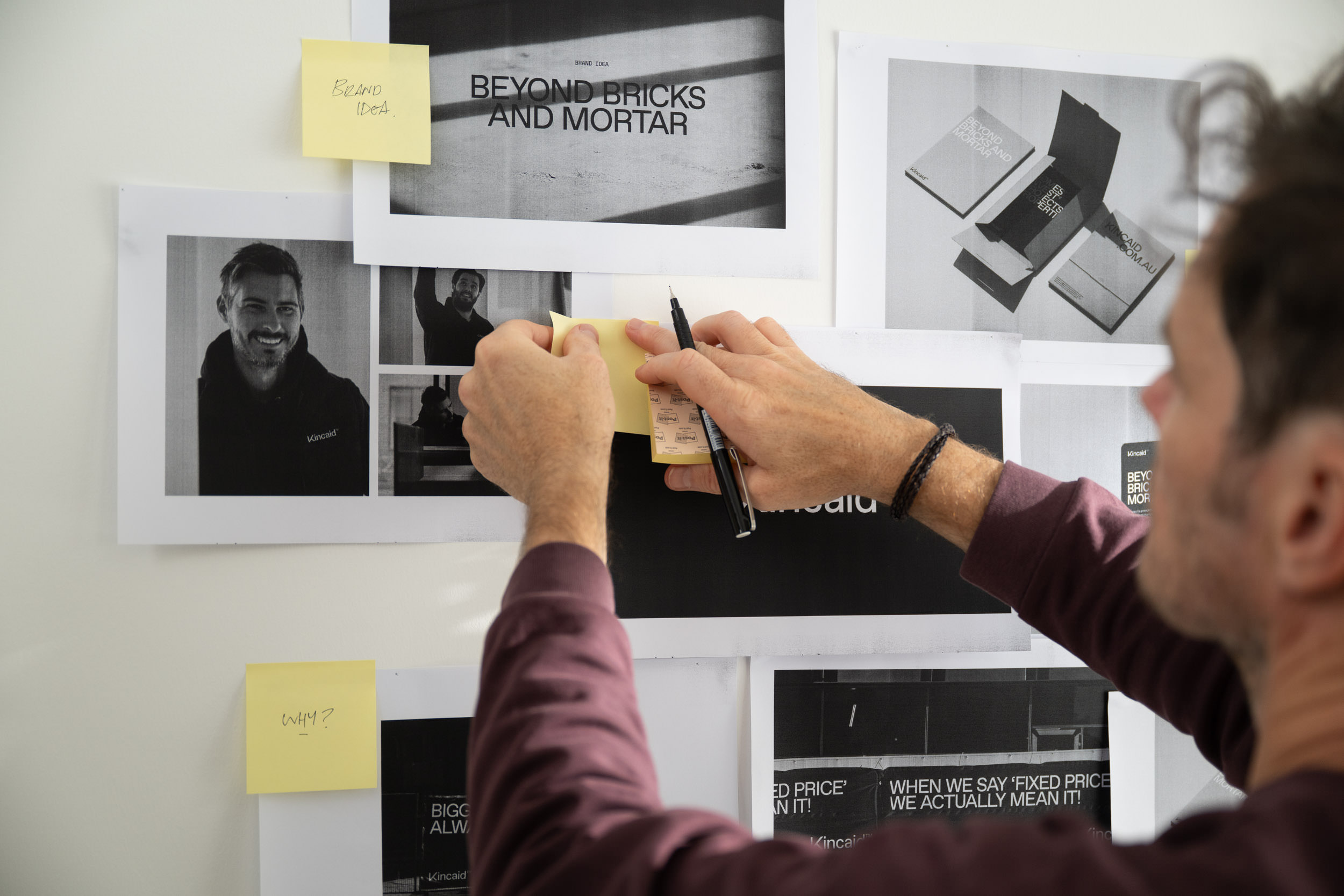 A critic session with the creative director sticking notes onto designs on a wall