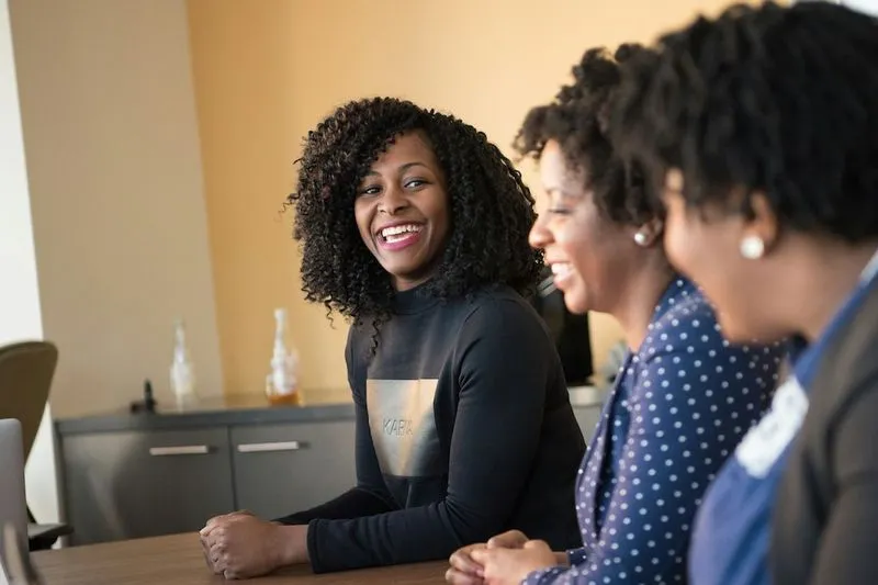 Three woman smiling at table.