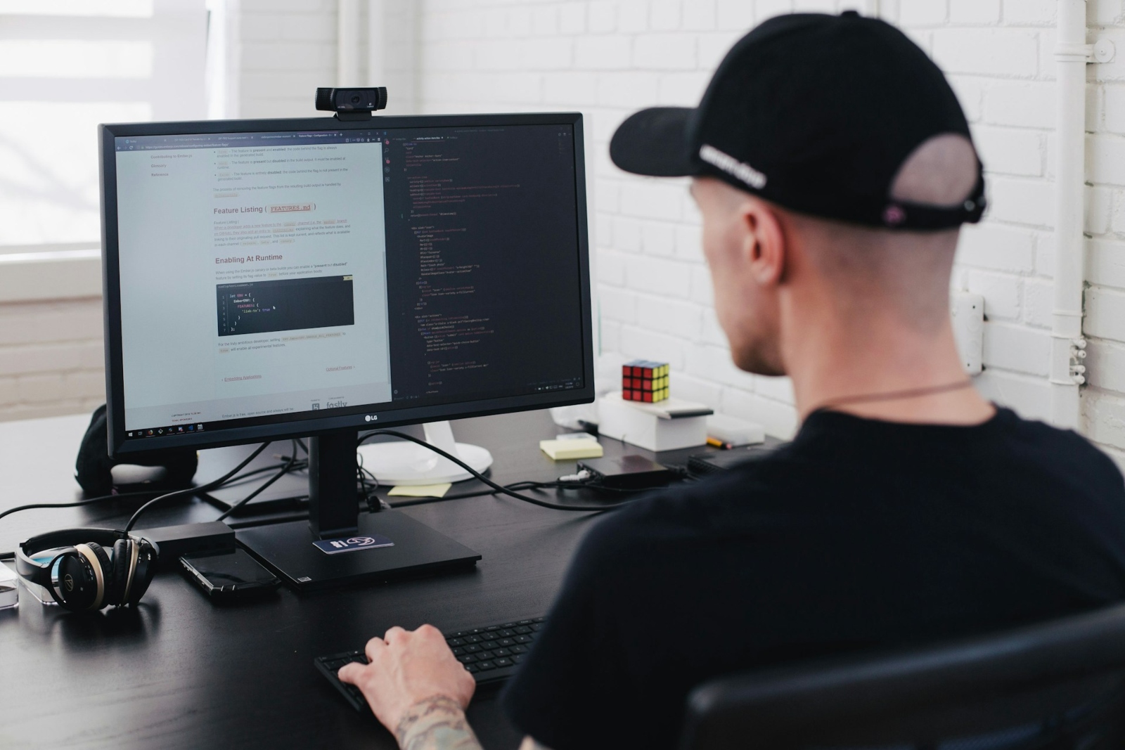 A man with a tattoo on his arm is typing on a computer.