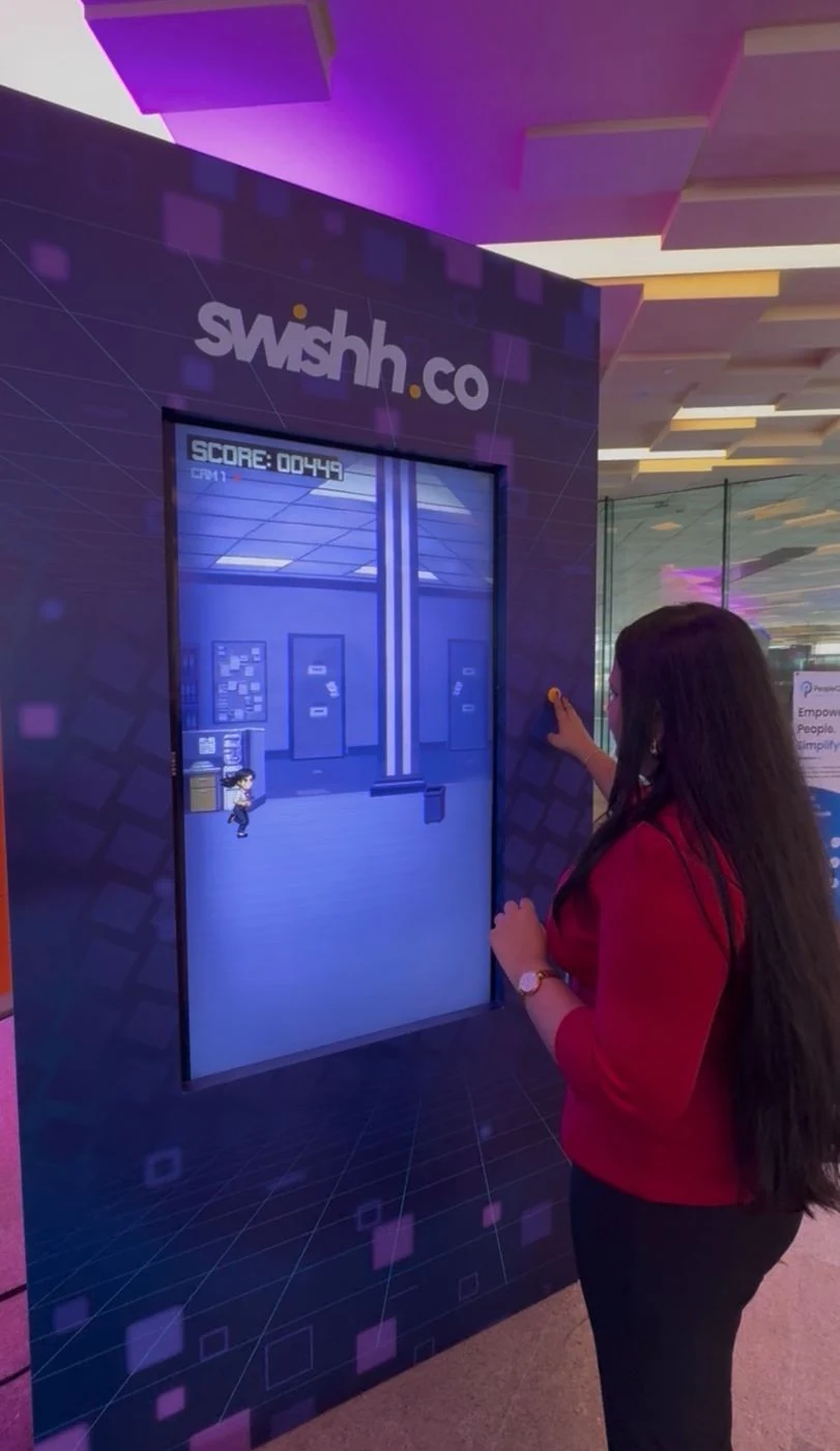 An attendee playing the office-themed jumping game on the branded arcade screen