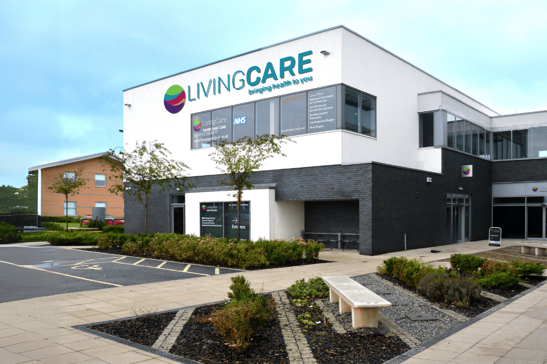 Modern two-story building with LivingCare Clinic signage and landscaped garden with benches in front.