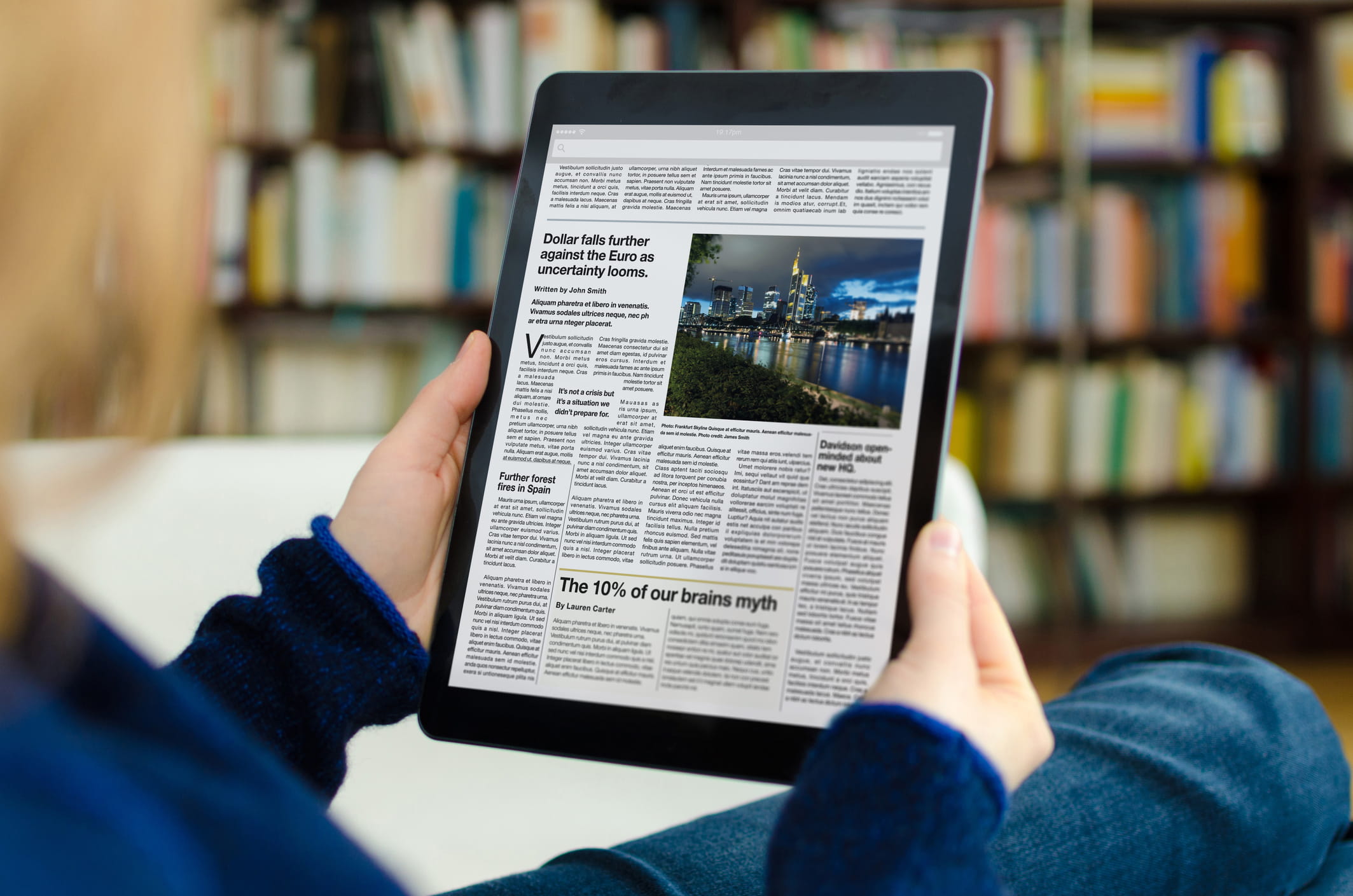 A person reading a news page on a tablet