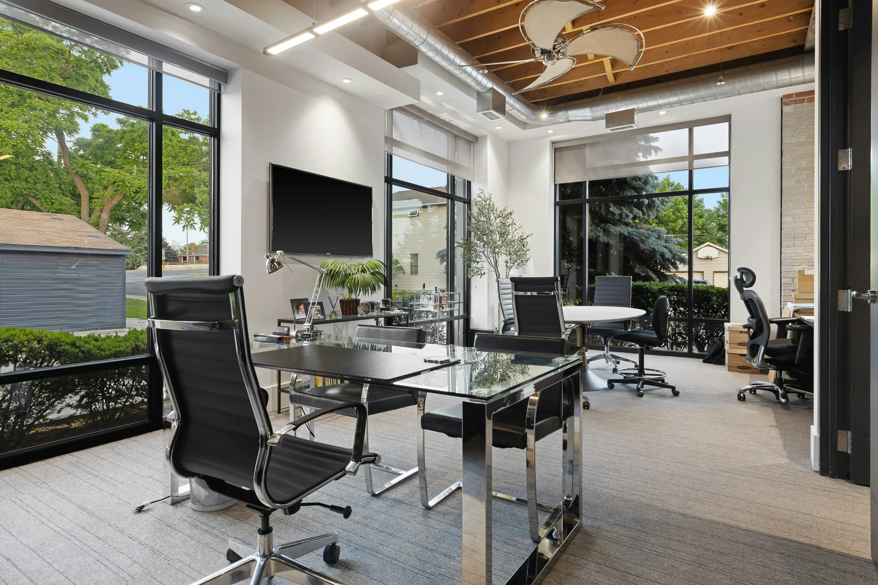 Renovated modern office with a glass conference table, black office chairs, and large windows.