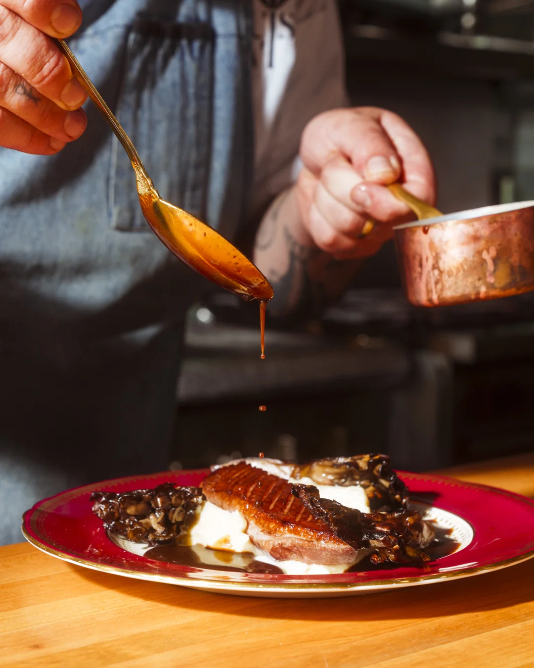 Le chef nappe de sauce un magret de canard au Bistro Le Louis XVI