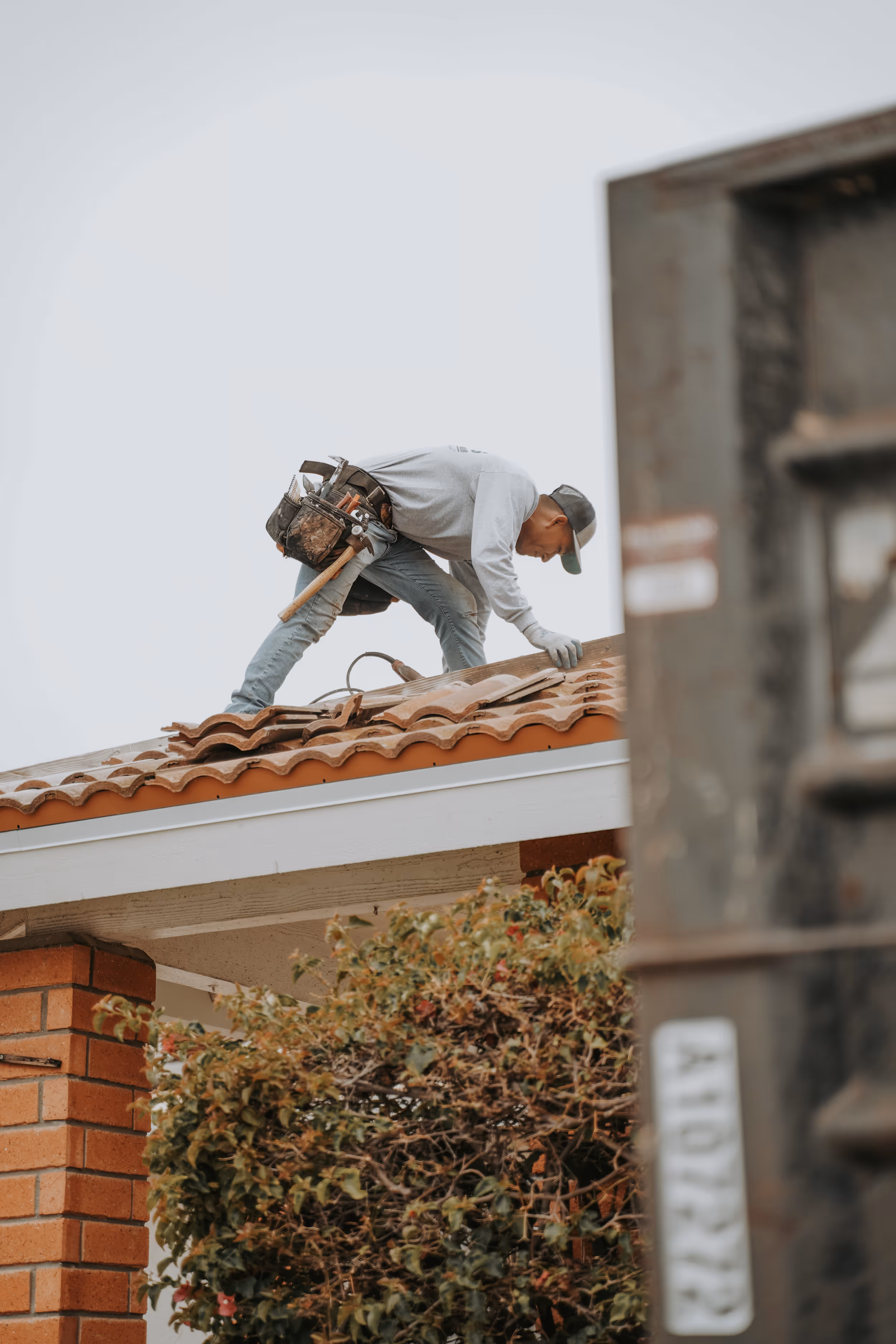 roofing contractor repairing clay tile roof on residential home
