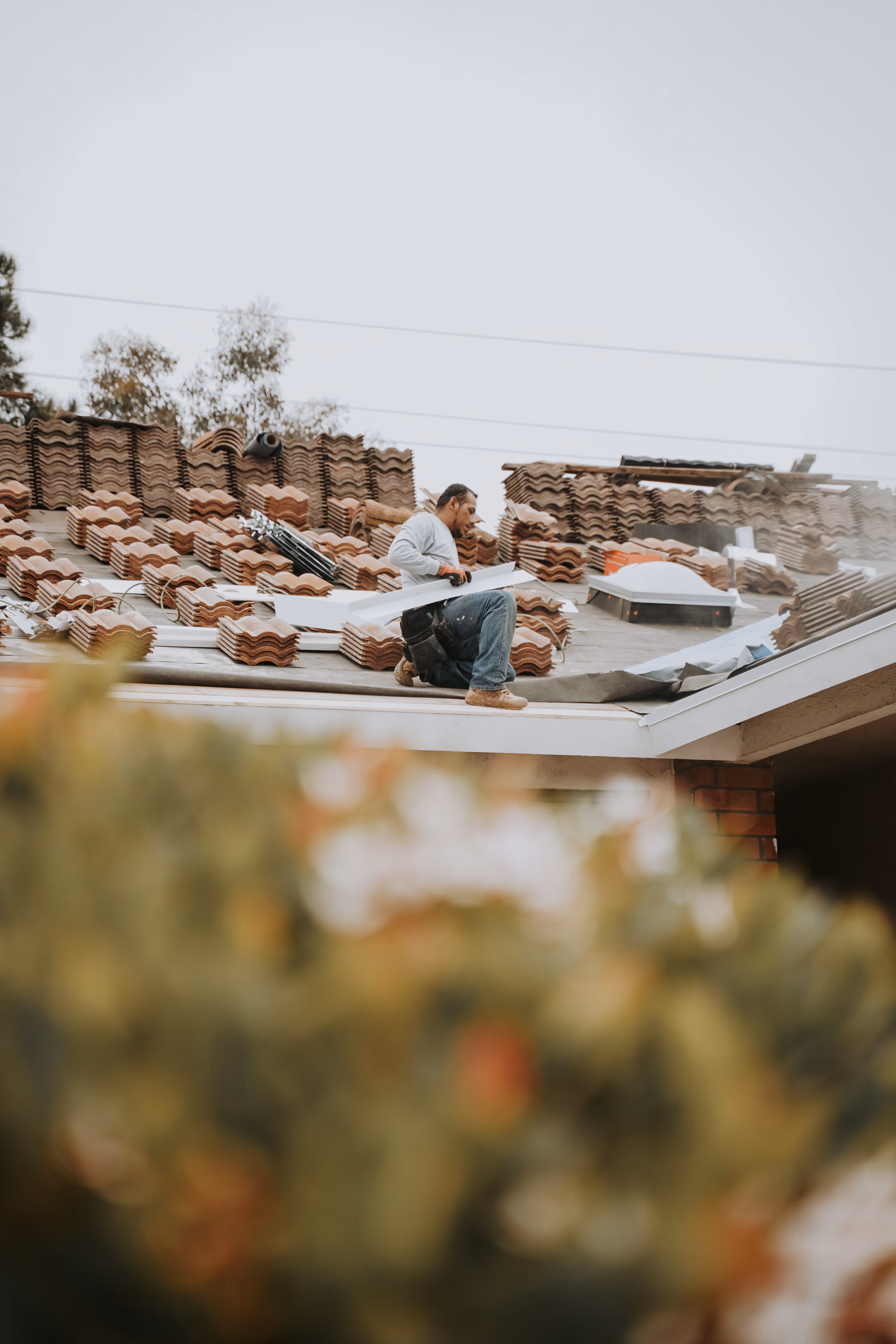 Tile roof replacement in progress with stacked clay tiles