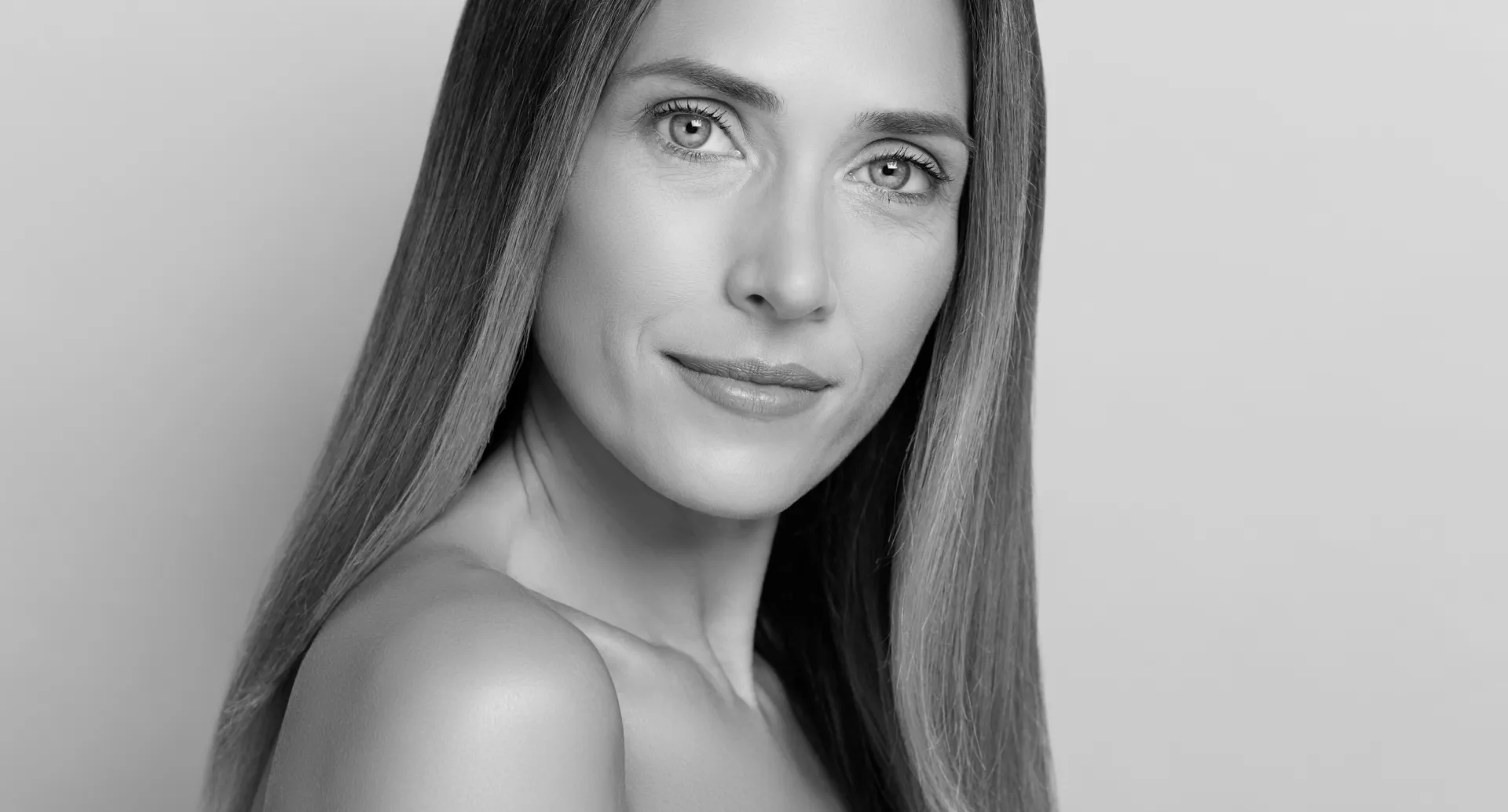 A smiling woman, looking at the camera.