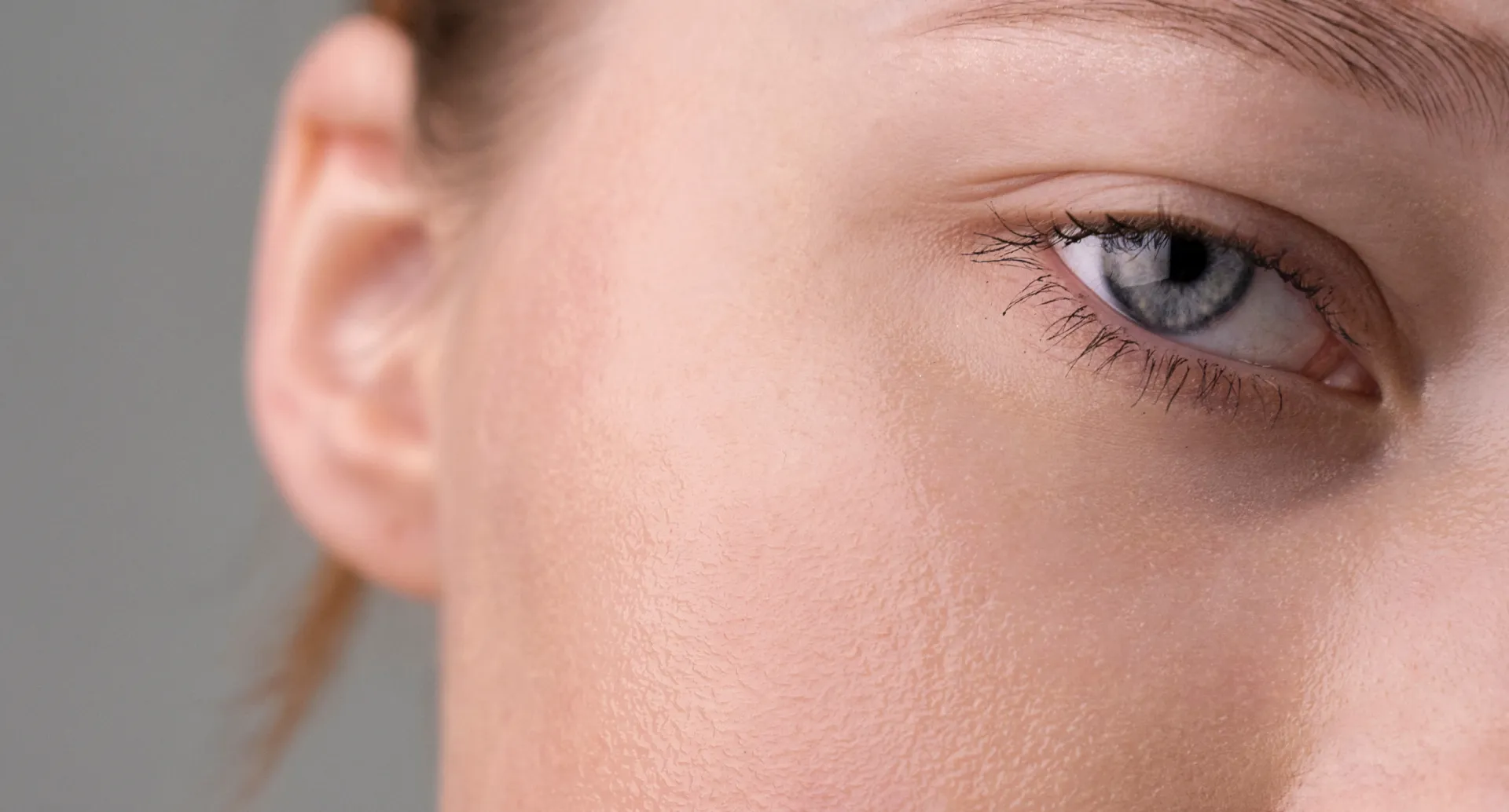Close-up of a blue eye and smooth skin on the side of a person's face.