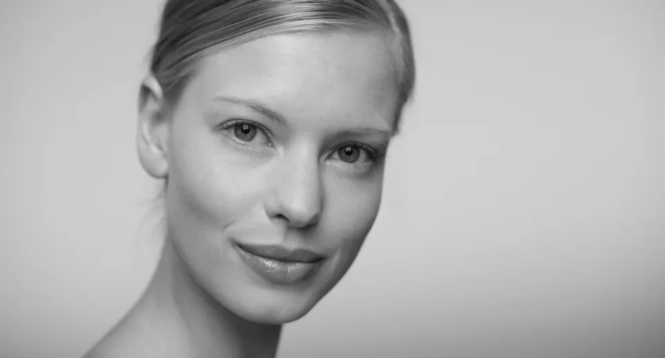 Close-up black and white portrait of a young woman with smooth skin and a slight smile.