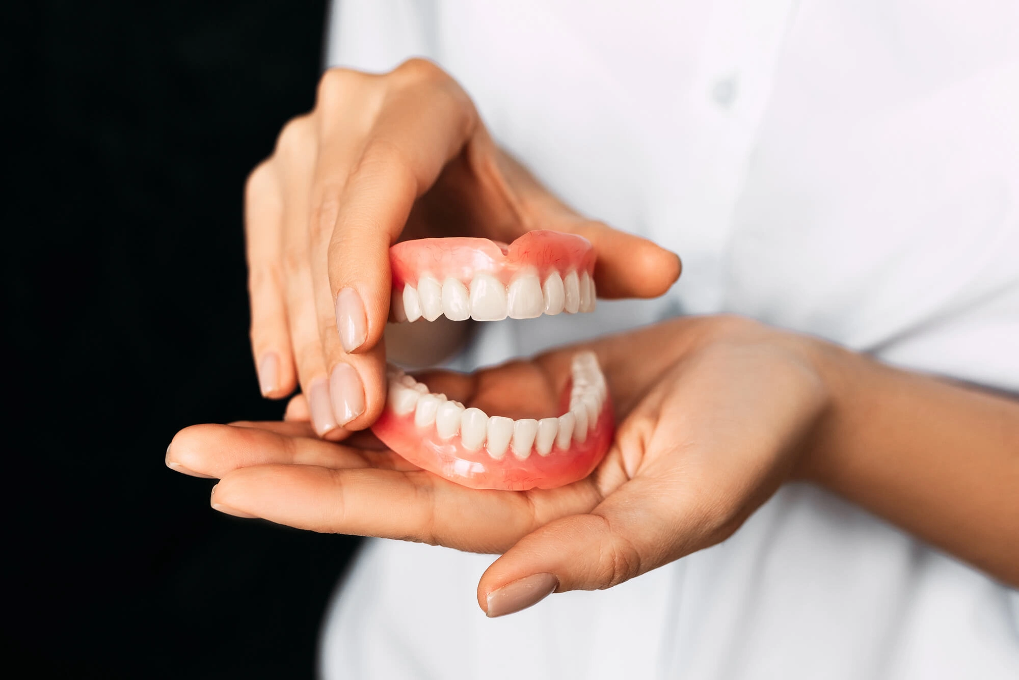 Dentist holding a model of fixed dentures steele creek nc