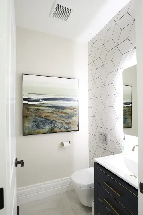 Powder room interior showing sink, mirror, and artwork hung on wall