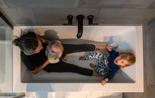 Overhead view of mom and two kids playing in empty bathtub