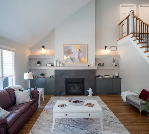 Pulled back view of great room sofa, fireplace, and staircase