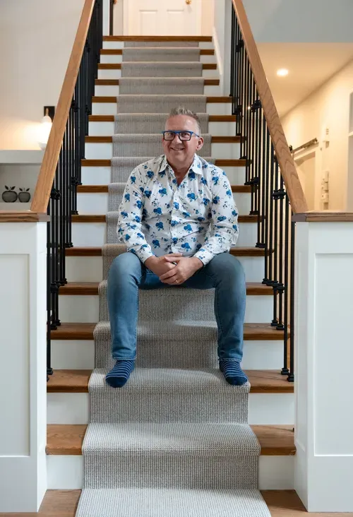Homeowner sitting on staircase smiling at camera