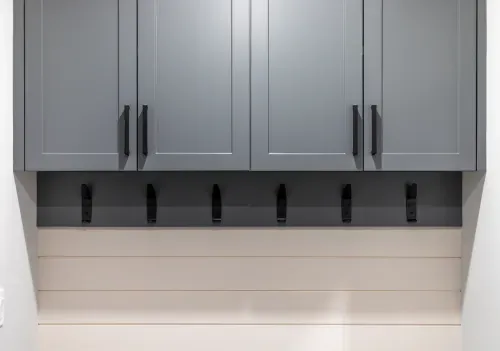 Close up of laundry room cabinets and clothing hooks