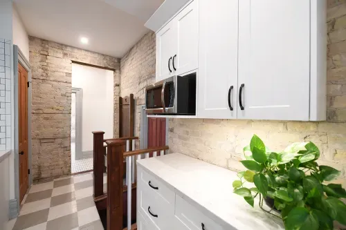 White kitchen cabinets on exposed brick wall
