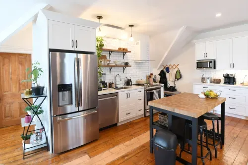 Second kitchen unit with fridge, white cabinetry, wooden island