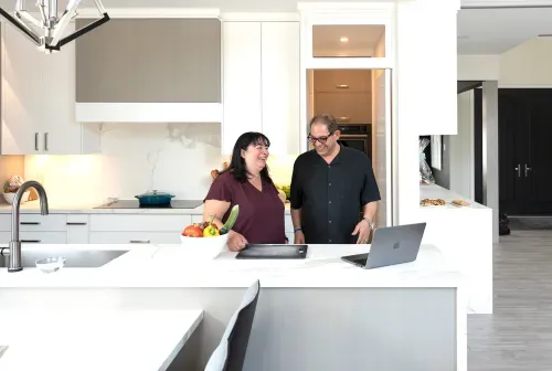 Homeowners laughing and preparing food together in kitchen