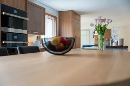 Wooden kitchen island countertop with fruit bowl and vase of flowers on top