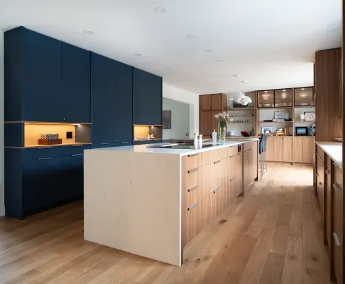 Angled view of kitchen with navy blue kitchen cabinets and white island